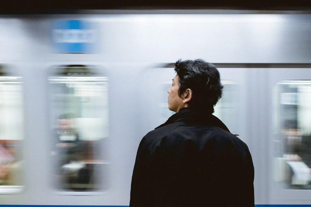 Person standing on a platform as a train speeds past in the background.