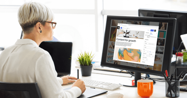 Woman with short hair and glasses edits content on a digital solution publishing dashboard.