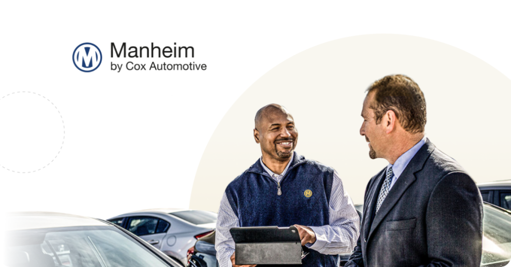 Two men discuss digital solution content integration by parked cars, one holding a tablet, Manheim logo visible.