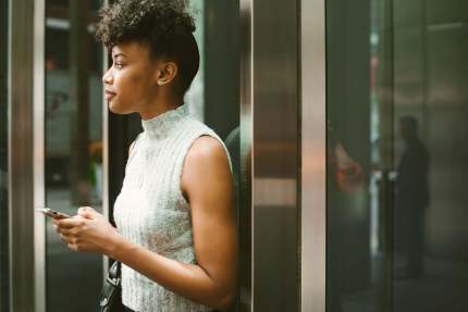 A person looking up from using a phone while in an elevator.