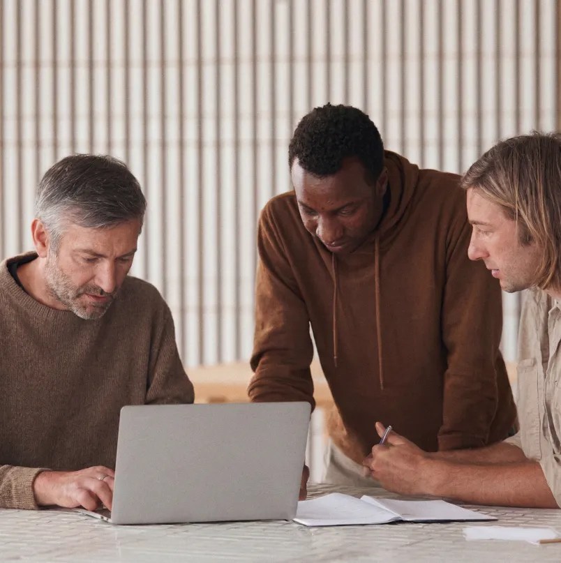 Three team members reviewing enterprise integration requirements together on a laptop, planning technology partner implementation within the WordPress VIP ecosystem.