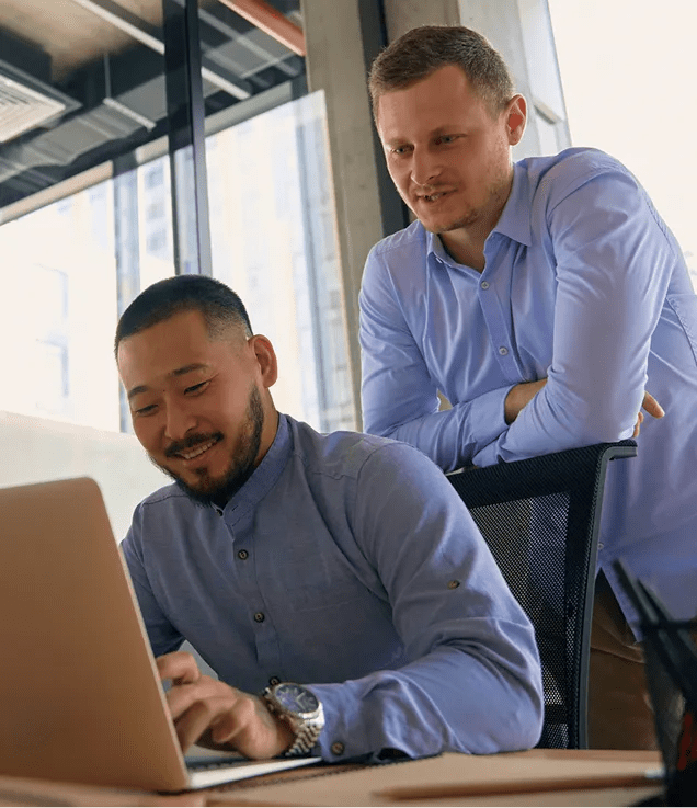 One colleague presenting information to another using a laptop.