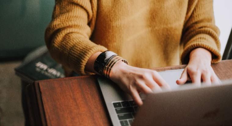 Person typing on a laptop, working on digital solution content or editorial workflow.