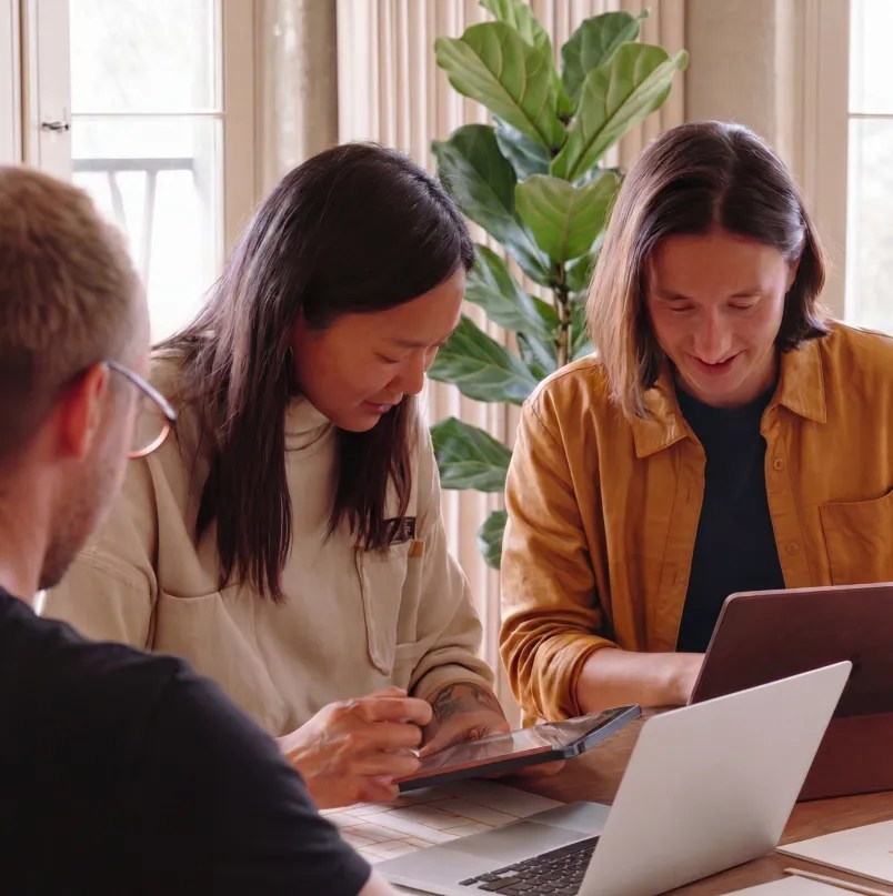 Three consultants collaborating with a laptop and tablet to plan an enterprise WordPress migration and implementation project delivered by a WordPress VIP service partner.