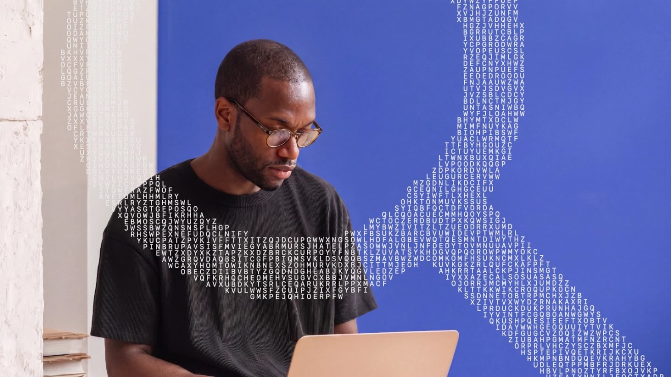 Man with glasses works on laptop; a search magnifier made of letters appears in the background against a blue wall, symbolizing the intricate connections of wordpress seo.