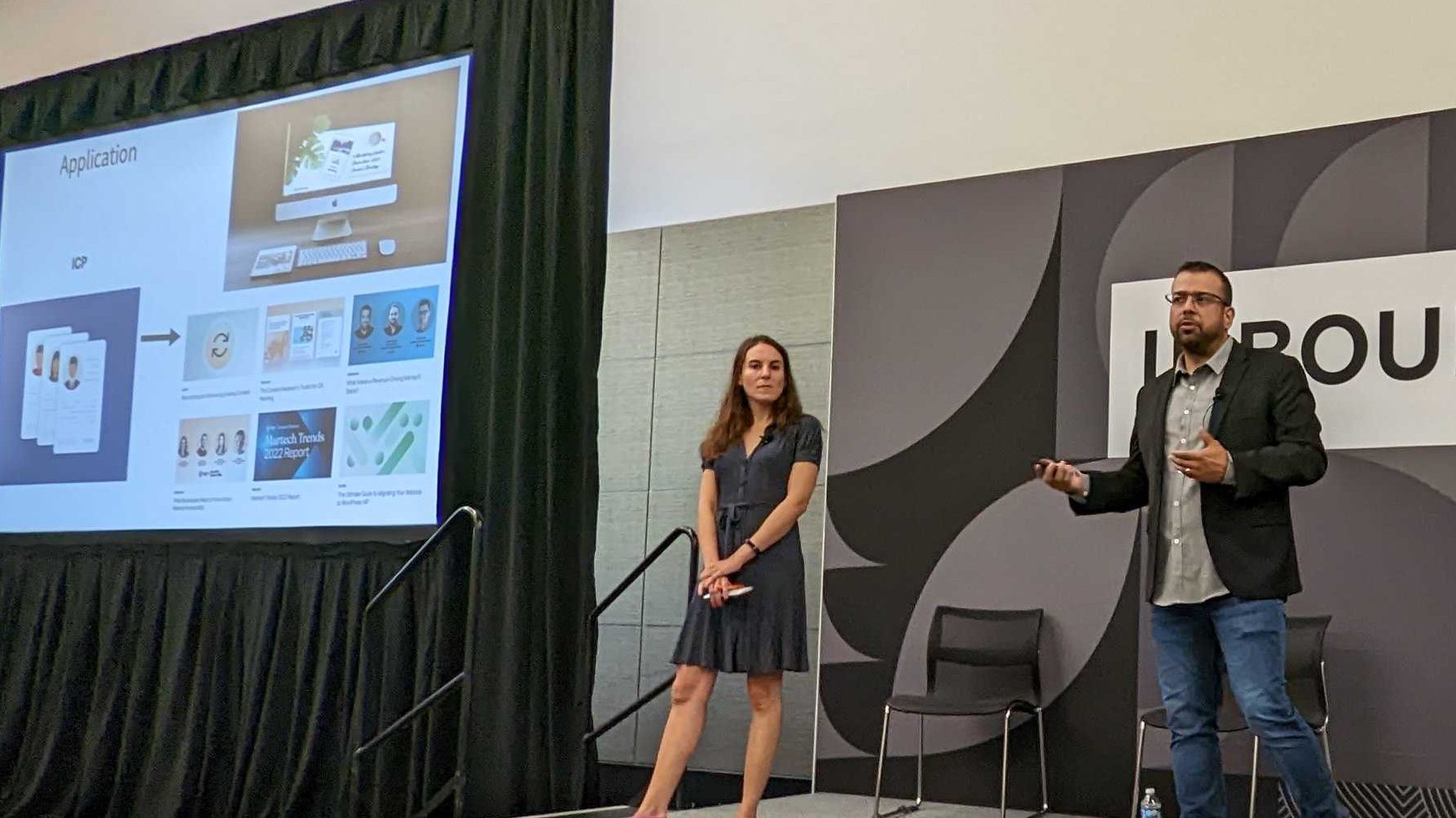 Stephanie and David on stage at the Inbound conference. A slide from the presentation is seen in the background.