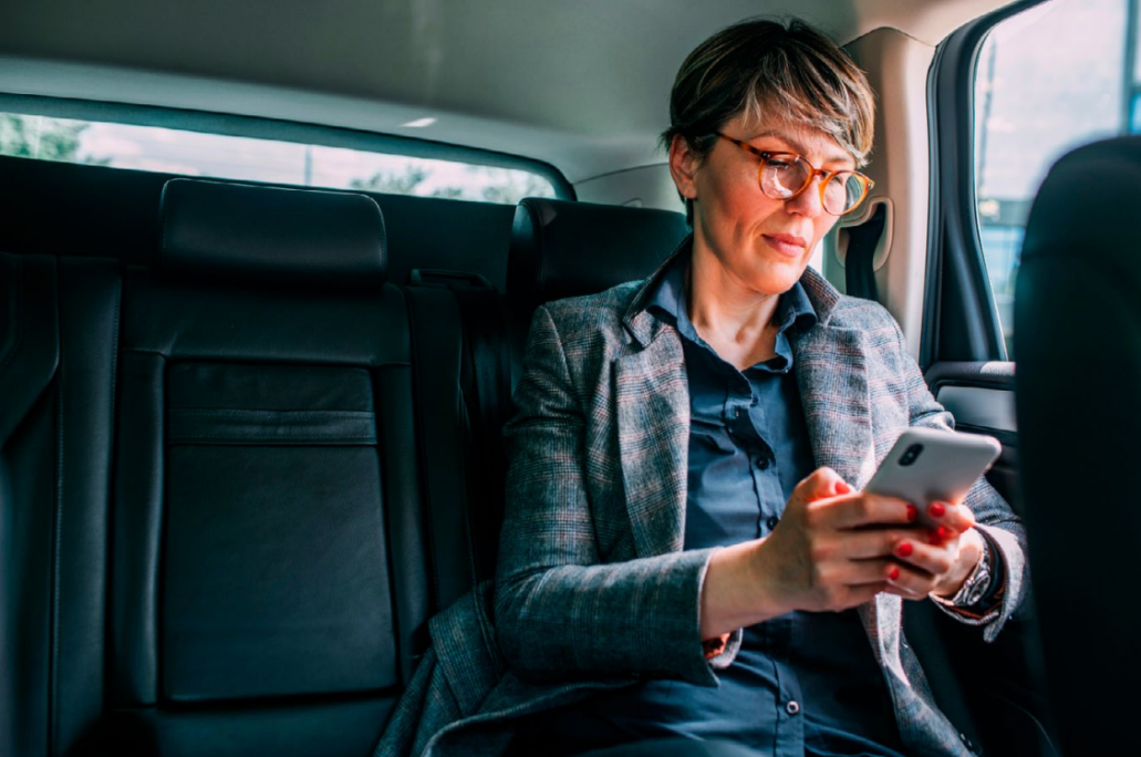 A person in a car, looking at a phone