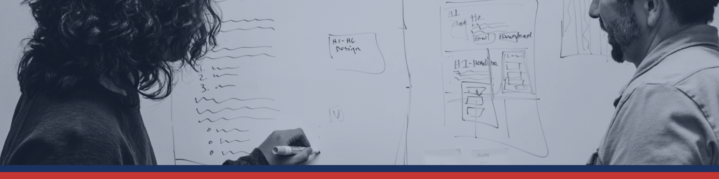 Two people looking at a whiteboard with numbers and boxes. 